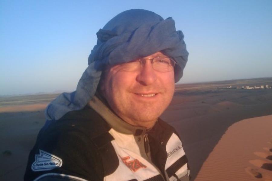 The author wearing a head scarf while looking across sand dunes