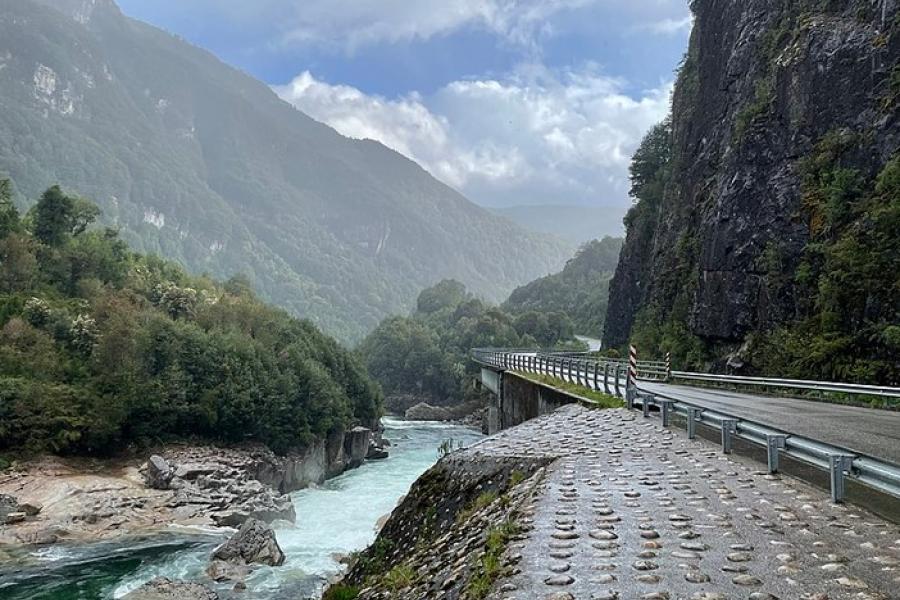 Carretera Austral, Chile - A paved bridge and highway next to a rugged stream in mountain terrain.