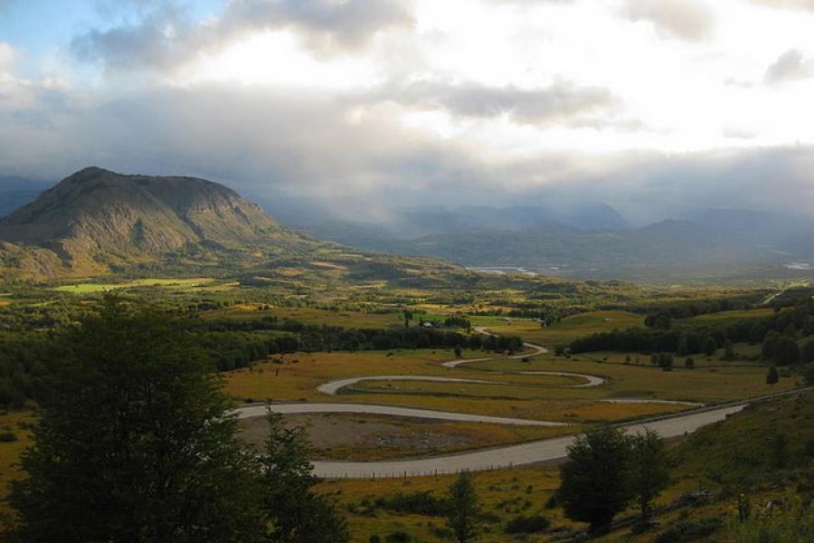 Carretera Austral, Chile - A long view of a winding road through a green, misty valley.